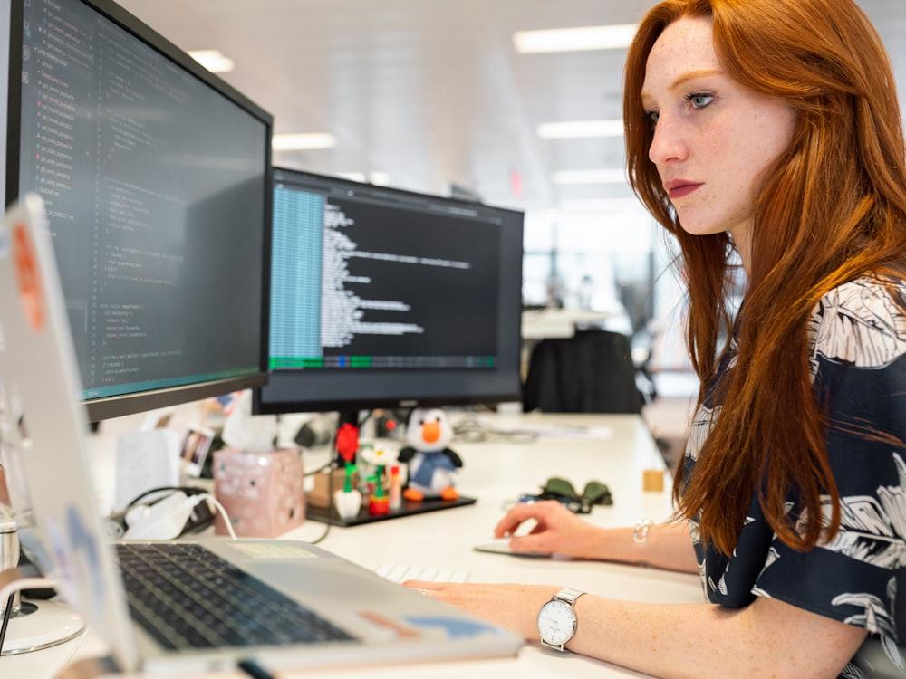 A developer working at her desk across two monitors
